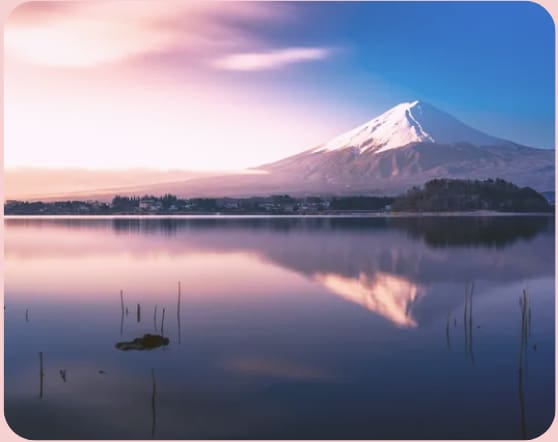 Snow-capped mountain reflected in calm pastel lake